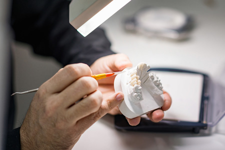 Dental technician or dentist working with tooth dentures in his laboratoryの写真素材