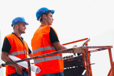 Construction workers operating on machineの写真素材