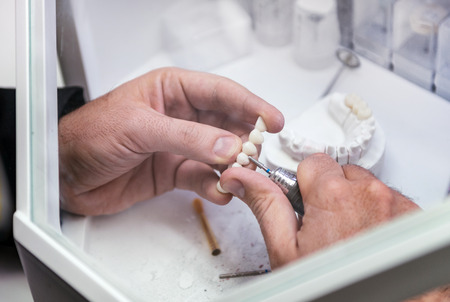 Dental technician or dentist working with tooth dentures in his laboratory
