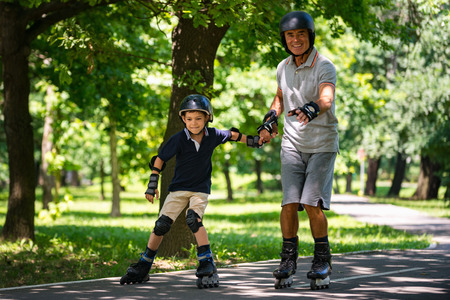 Grandfather and grandson enjoying roller skating in the park