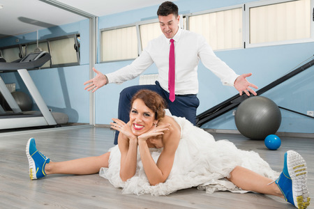 Bride streching and groom standing under herの写真素材