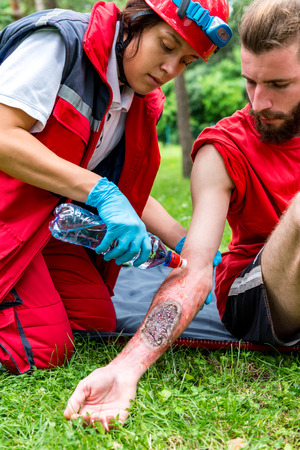 Medical worker treating burns on male's hand. First aid treatment outdoors. First aid practiceの写真素材
