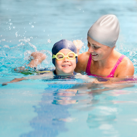 Little boy learning to swim with instructor's helpの写真素材
