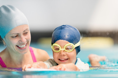 Happy little boy on swimming class with instructorの写真素材