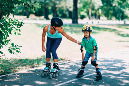 Mother teching son roller skating in parkの写真素材