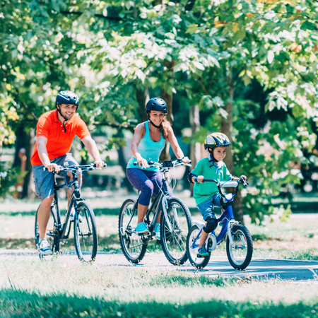 Cheerful family biking in parkの写真素材