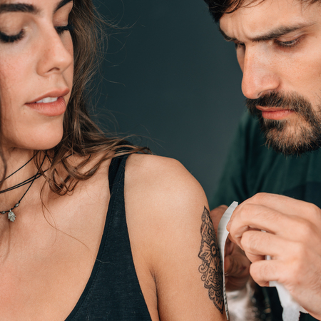 Temporary tattoo. Professional make-up artist applying temporary tattoo sticker to model's armの写真素材