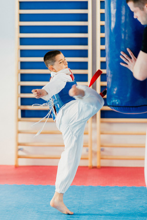 Child kicking punching bag on tae kwon do classの写真素材