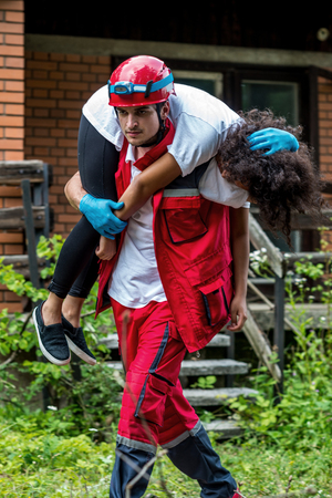 Rescue worker evacuate female victim from houseの写真素材