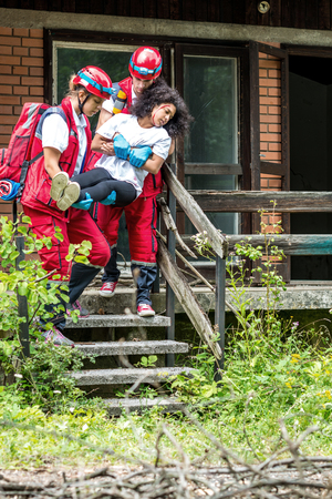 Rescue team evacuate female victim from houseの写真素材