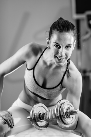 Young exercising with weights in the gymの写真素材