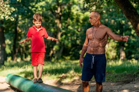 Grandfather and grandson walking on wooden huddle in parkの写真素材