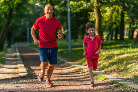 Grandfather and grandson jogging in parkの写真素材