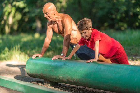 Grandfather and grandson doing pushups in parkの写真素材