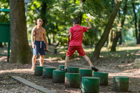 Grandfather and grandson walking on wooden huddles in parkの写真素材