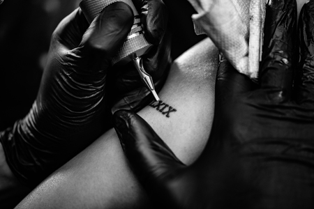 Tattoo artist tattooing young woman