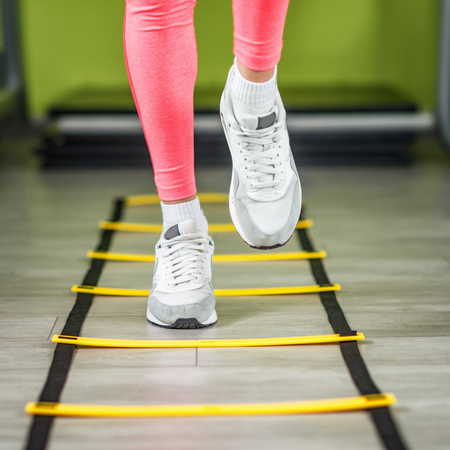 Young woman exercising on ladders in the gym
