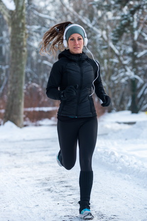 Female athlete jogging on park on winter day in parkの写真素材