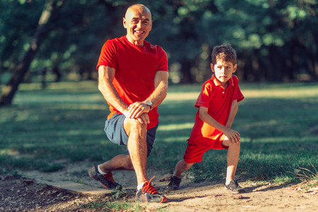 Grandfather and grandson warming up before exercising in parkの写真素材
