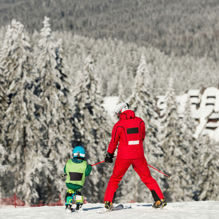 Skiing down the mountain with ski instructor and little boyの写真素材
