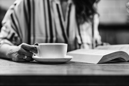 Woman drinking coffee and reading bookの写真素材