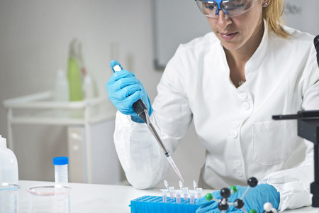 Young female scientist holding pipette in the lab wearing protective equipmentの写真素材