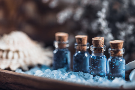 Aromatherapy. Close up photo of wooden and blue spa setting for aromatherapy. Essential oils, sea salt, wooden bowls, white flowers backgroundの写真素材
