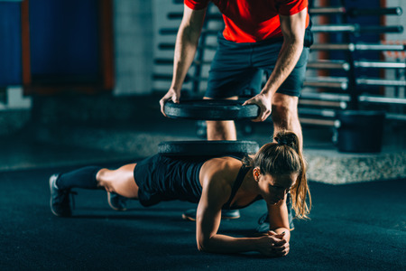 Cross training. Young athlete hodling heavy barbells on her back