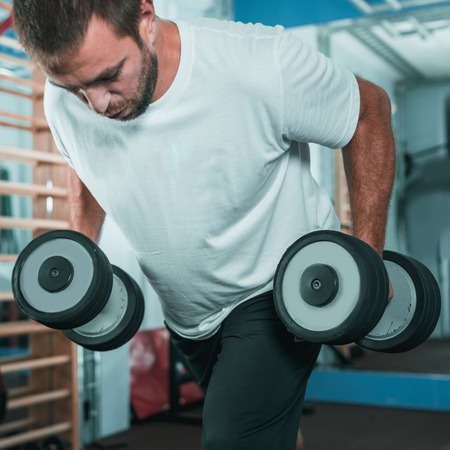 Peronal trainer with male client exercising in the gym 