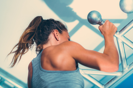 Female athlete doing pull-ups in the gym