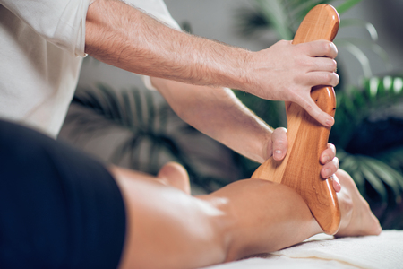 Close up of therapist doing anti cellulite Madero therapy massage to sporty young womanの写真素材