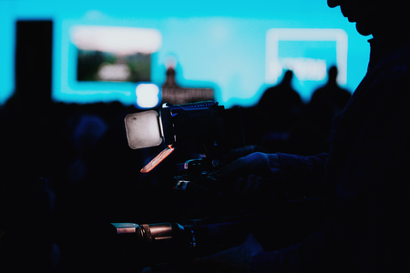 Professional digital camera silhouette recording audience at media press conference blurred speaker, live streaming conceptの写真素材