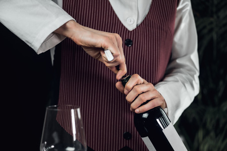 Female sommelier opening wine bottle with corkscrewの写真素材
