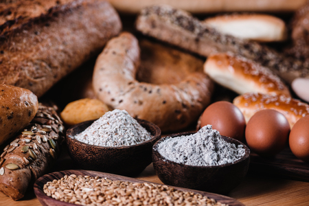Integral flour and rye grains in wooden bowls, baking ingredients, close upの写真素材