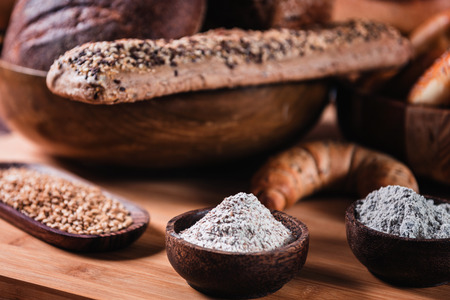 Integral flour and rye grains in wooden bowls, close upの写真素材