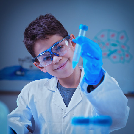 Boy in lab coat holding test tube, experimenting in the school