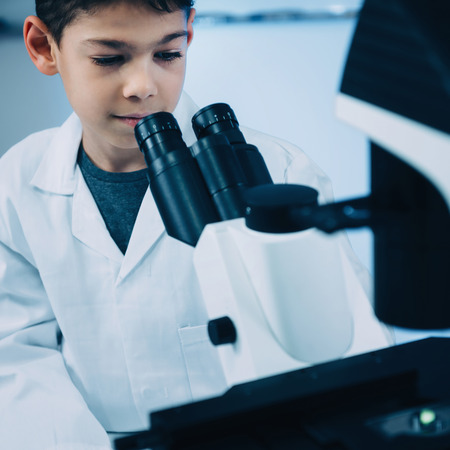 Schoolboy using laboratory microscopeの写真素材