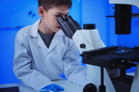 Schoolboy using laboratory microscopeの写真素材