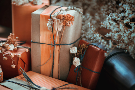 Horizontal composition with gift boxes wrapped in natural color paper, tied with twine, decorated with dried flowers.の写真素材