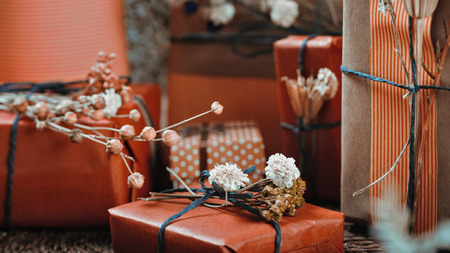Horizontal composition with gift boxes wrapped in natural terracotta color paper, tied with twine,...