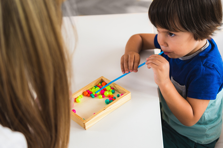 Child psychology, little boy blowing beads with strawの写真素材