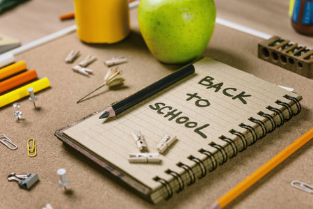 Horizontal composition with school supplies. Recycle paper notebook, green apple, sharpener and...