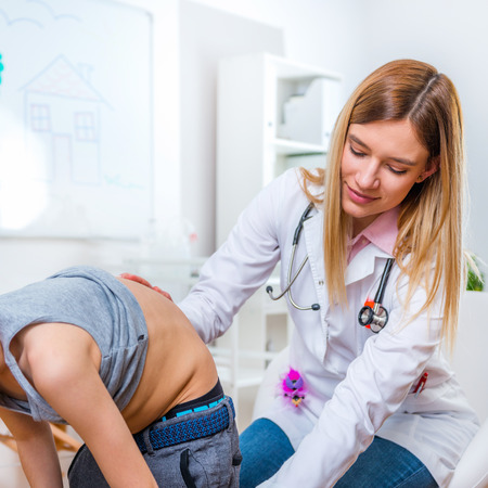 Pediatrician examining boy's spineの写真素材