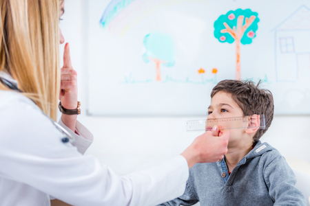 Pediatrician examining boyâs eyes with rulerの写真素材