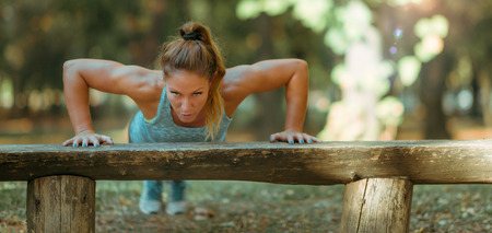 Woman doing push ups in the park, in the fall in Public Park