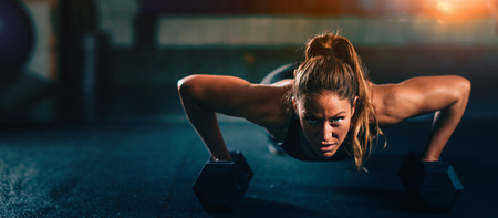 Cross training. Young woman exercising with dumbbells