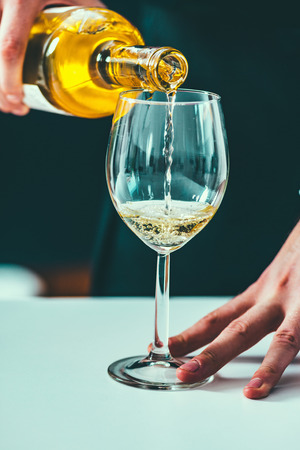 Pouring white wine from bottleの写真素材