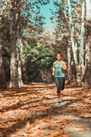 Woman Jogging Outdoors in The Fall, in Public Parkの写真素材