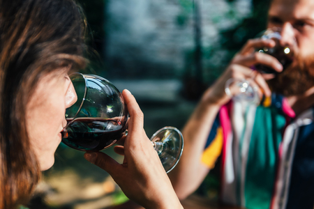 Young couple enjoying romantic wine tasting on a date. Couple wearing colorful outfit. Outdoor restaurant in background.の写真素材