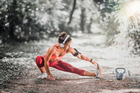 Young woman stratching after jogging in the park